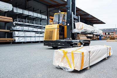 Ein Gabelstapler transportiert Holzbretter vor dem Lager von JACOB CEMENT BAUSTOFFE